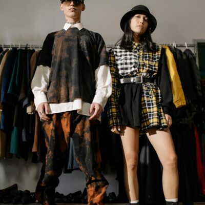 Two individuals pose confidently in a vintage clothing store showcasing urban fashion style.